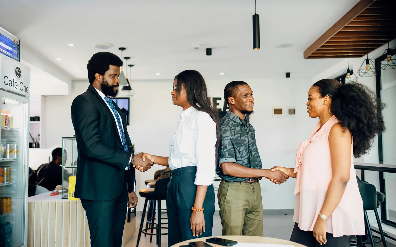 Profissionais africanos a cumprimentar-se num espaço de trabalho moderno
